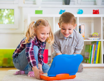 Cute sibling playing with toy while sitting at home