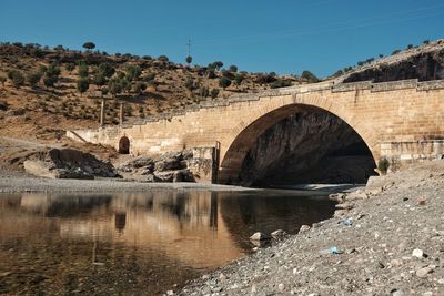 Arch bridge over river against sky