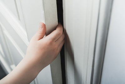 Close-up of hand holding glass window at home