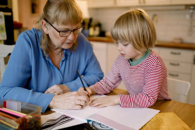 Grandmother assisting grandson in studying at home