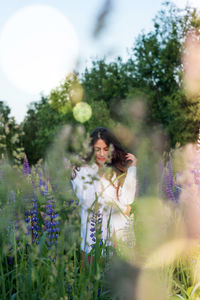 Woman standing on purple flowering plants on field