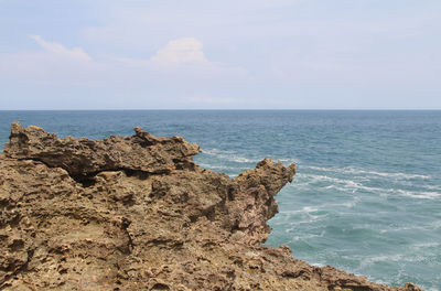 Rock formation on beach against sky