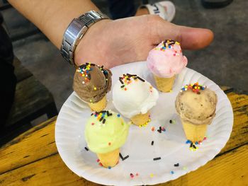 High angle view of hand holding cake on table