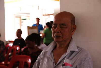 Senior man with eyes closed leaning against wall
