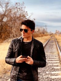 Young man smoking while standing on railroad track