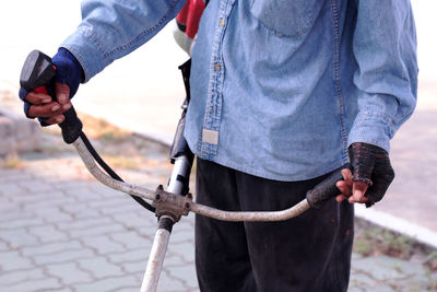 Midsection of man holding metal