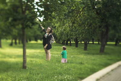 Baby girl looking at mother standing by tree at park
