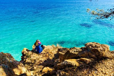 Woman sitting on rock by sea