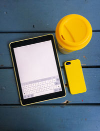 Close-up of tablet computer and mobile smart phone with takeout coffee in yellow and blue colors.