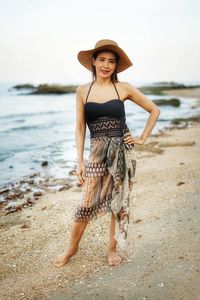 Portrait of young woman wearing hat while standing at beach
