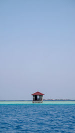 A hut in sea against clear sky