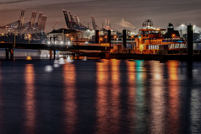 Illuminated pier by harbor at night