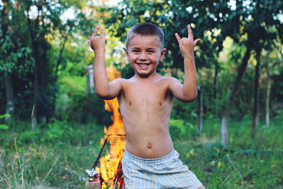 Portrait of happy boy gesturing while standing against bonfire