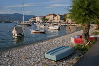 Sailboats moored on sea against sky in city