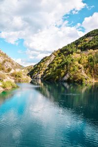 Scenic view of lake by mountains against sky