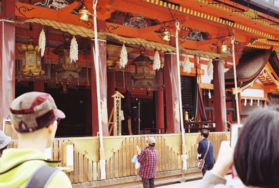 Rear view of people walking outside temple against building