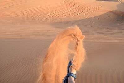 Low section of man kicking sand at desert