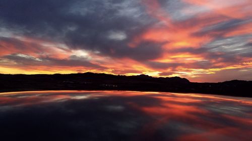 Scenic view of dramatic sky over lake during sunset