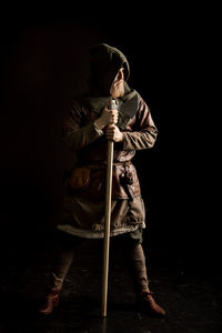 Viking with axe standing against black background