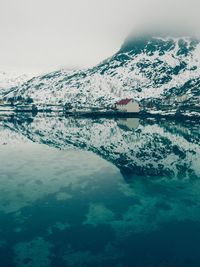 Scenic view of sea by snowcapped mountain against sky