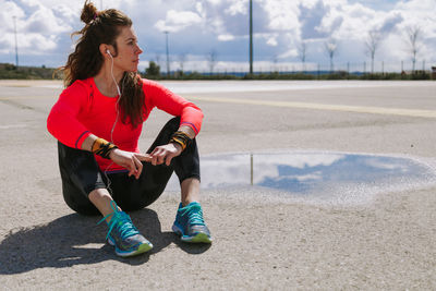 Full length of young woman sitting on road