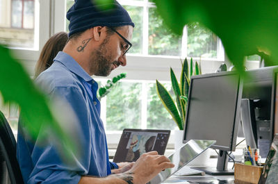 Side view of man using mobile phone while sitting on table