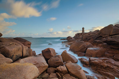 Rocks in sea against sky during sunset