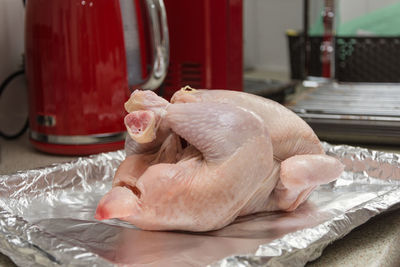 Close-up of raw chicken on baking sheet at table