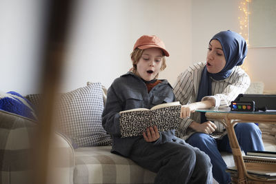 Mother wearing hijab helping son doing homework