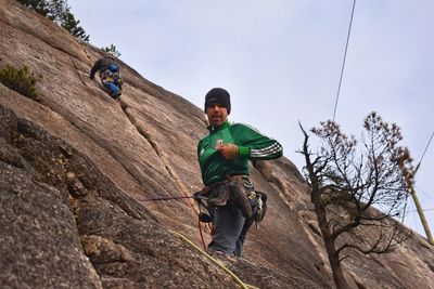 Full length portrait of young man standing on rock against sky