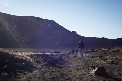 Rear view of people walking on land against sky