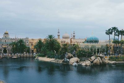 Buildings at waterfront against cloudy sky