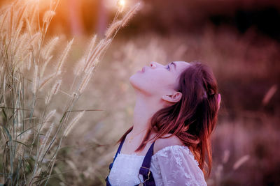 Side view of beautiful woman with head back on field