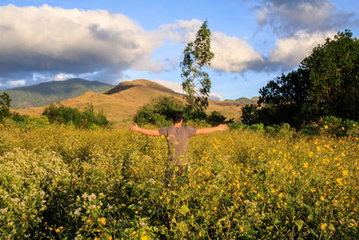 Man standing on field by plants against sky