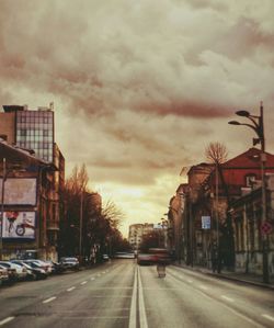 Cars on road against cloudy sky