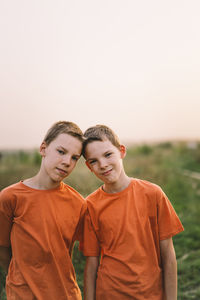 Funny twin brother boys playing outdoors on field at sunset.