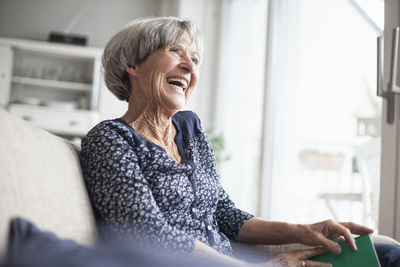 Portrait of happy senior woman sitting on couch at home