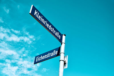 Low angle view of road sign against blue sky