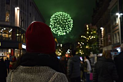 Rear view of woman in warm clothes in city at night