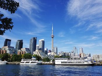 Modern buildings by river against sky in city