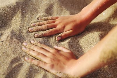 High angle view of hands on sand