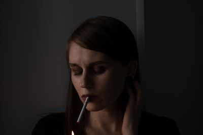 Close-up portrait of a young woman over black background