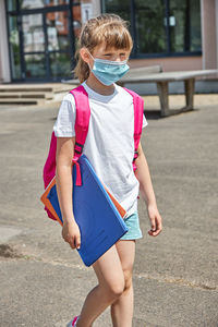 Back to school. a girl in a protective mask with a knapsack goes to school after summer holidays. 