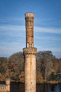 Tower by river against sky