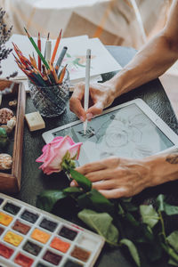 Midsection of person holding paper painting on table