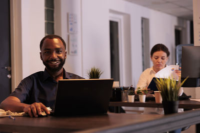 Portrait of businessman using laptop at office