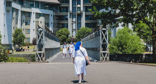 Rear view of people walking on street in city