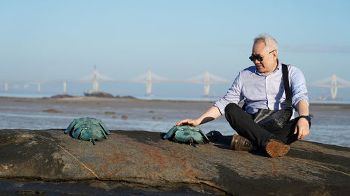 Portrait of man sitting on rock at beach