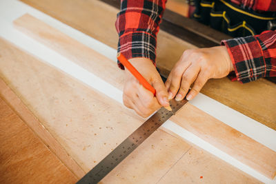 Cropped hands of man tying shoelace on hardwood floor