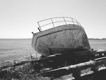 Rusty metallic structure by sea against clear sky